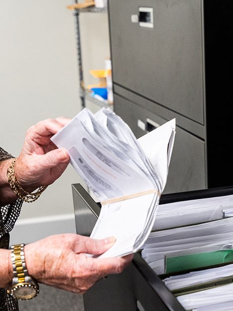 Hands of local Florida staff sifting through files and mail.